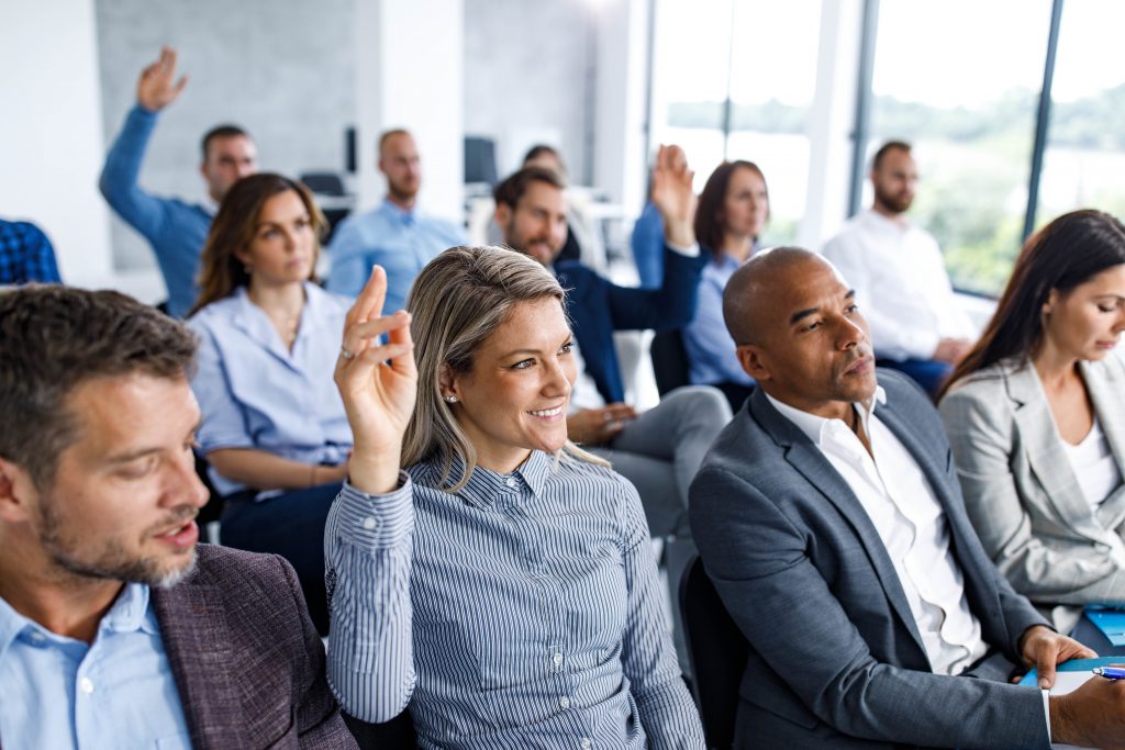 A room with people asking questions after a presentation