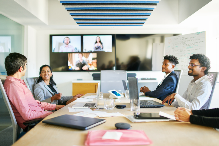 Cisco WebEx – Smiling young businesspeople talking during a video conference call in a boardroom